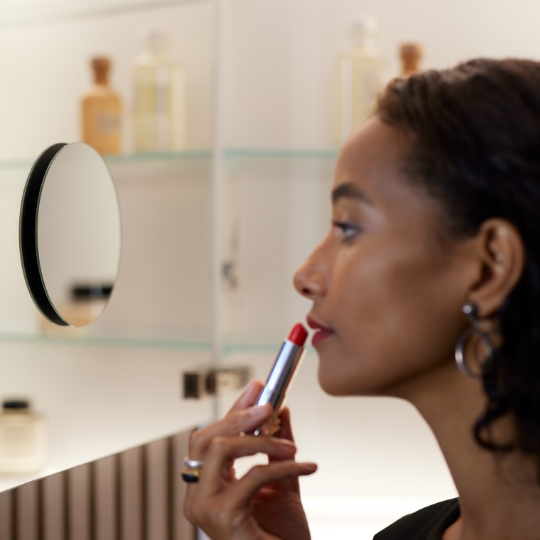 Prikaz žene koja upotrebljava ogledalo za šminkanje